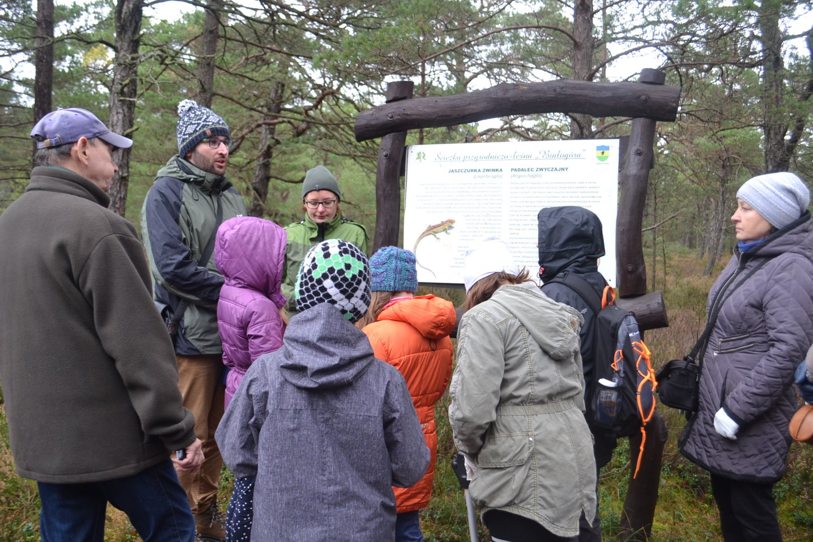 Uczestnicy zebrani przy tablicy edukacyjno – informacyjnej, poznają walory przyrodnicze rezerwatu