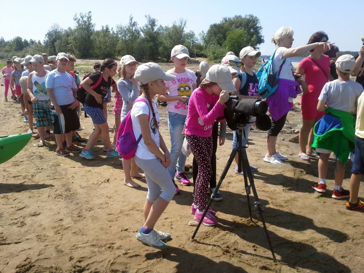 Grupa uczniów przez lunetę ogląda ptaki w rezerwacie przyrody Mewia Łacha